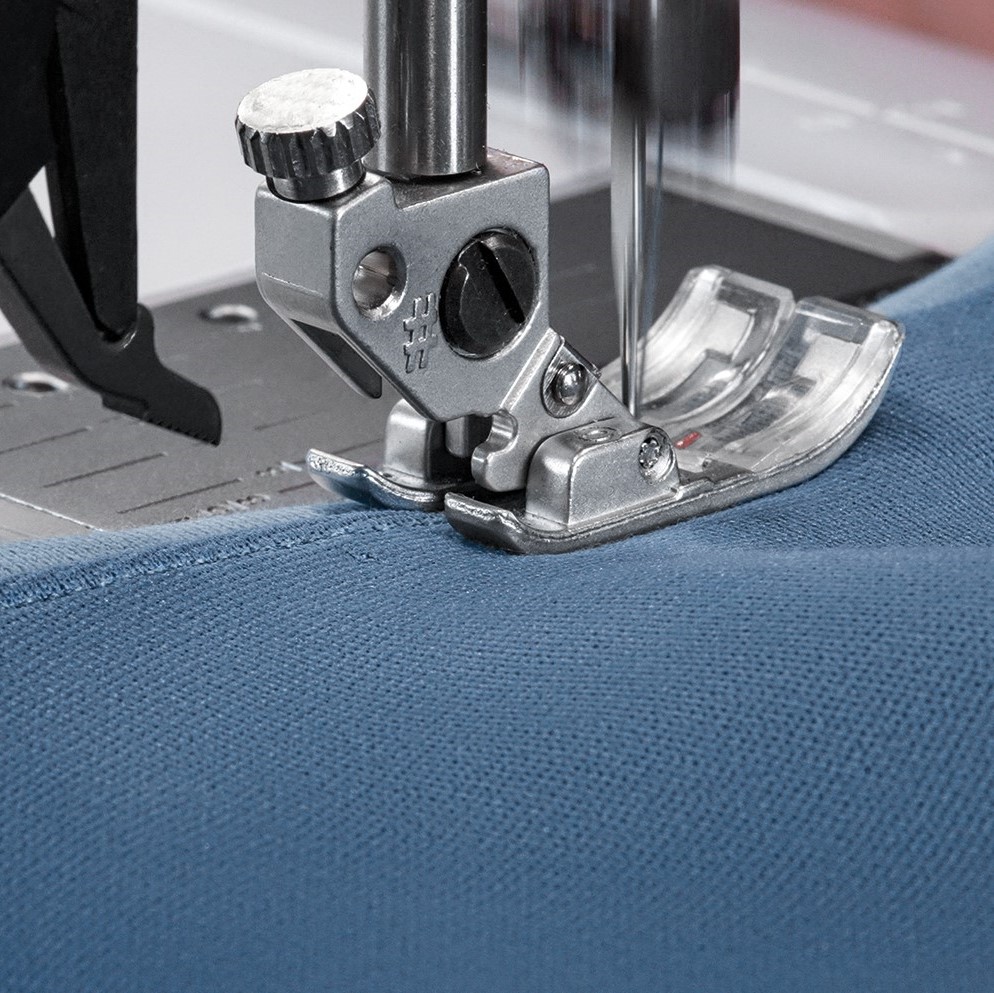 A piece of blue fabric being sewn on a sewing machine with Maraflex